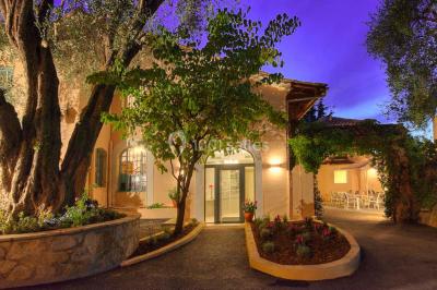 Chambre lumineuse avec un mur rose, deux fauteuils fuchsia, un lit double et des meubles blancs avec miroirs.