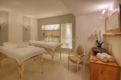 Chambre lumineuse avec un mur rose, deux fauteuils fuchsia, un lit double et des meubles blancs avec miroirs.