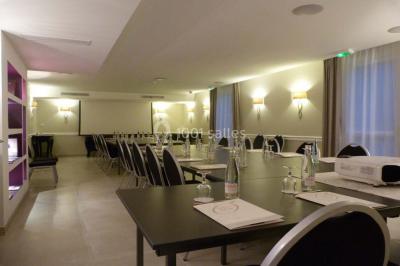 Chambre lumineuse avec un mur rose, deux fauteuils fuchsia, un lit double et des meubles blancs avec miroirs.