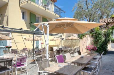 Chambre lumineuse avec un mur rose, deux fauteuils fuchsia, un lit double et des meubles blancs avec miroirs.