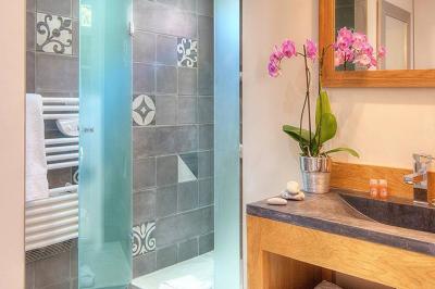 Chambre lumineuse avec un mur rose, deux fauteuils fuchsia, un lit double et des meubles blancs avec miroirs.