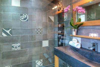 Chambre lumineuse avec un mur rose, deux fauteuils fuchsia, un lit double et des meubles blancs avec miroirs.