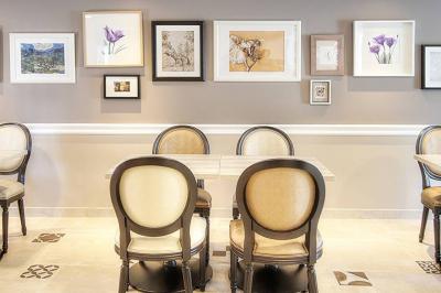 Chambre lumineuse avec un mur rose, deux fauteuils fuchsia, un lit double et des meubles blancs avec miroirs.