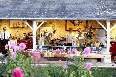 Un stand culinaire en plein air avec des chefs préparant des plats, entouré de fleurs et d'une structure en bois.