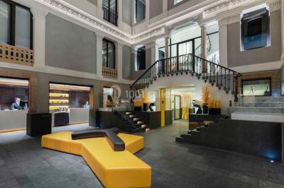 Salle de bain moderne avec douche vitrée, lavabo blanc, miroir rond, fleurs jaunes et mur bleu texturé.