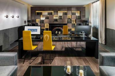 Salle de bain moderne avec douche vitrée, lavabo blanc, miroir rond, fleurs jaunes et mur bleu texturé.