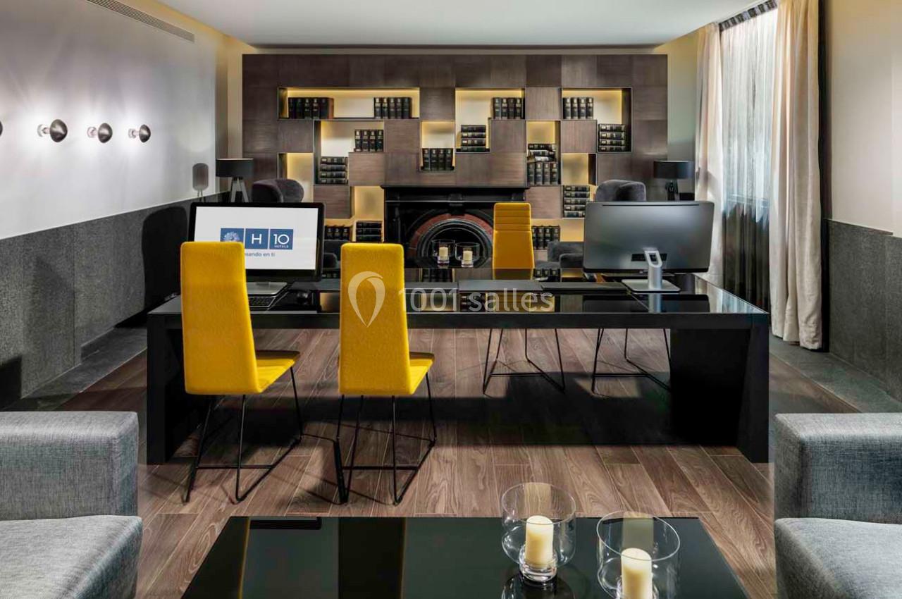 Bureau moderne avec deux postes de travail, chaises jaunes, étagères décorées et lumière naturelle.