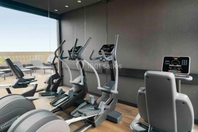 Salle de bain moderne avec douche vitrée, lavabo blanc, miroir rond, fleurs jaunes et mur bleu texturé.