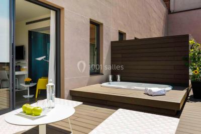 Salle de bain moderne avec douche vitrée, lavabo blanc, miroir rond, fleurs jaunes et mur bleu texturé.