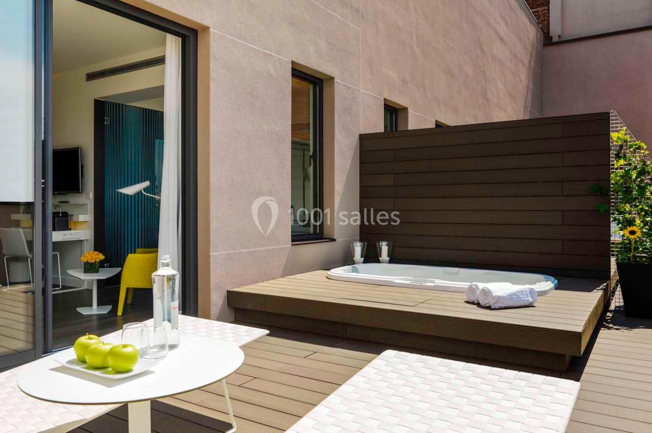 Terrasse avec jacuzzi encastré, table avec pommes vertes et serviettes, entourée de murs en bois et en pierre.