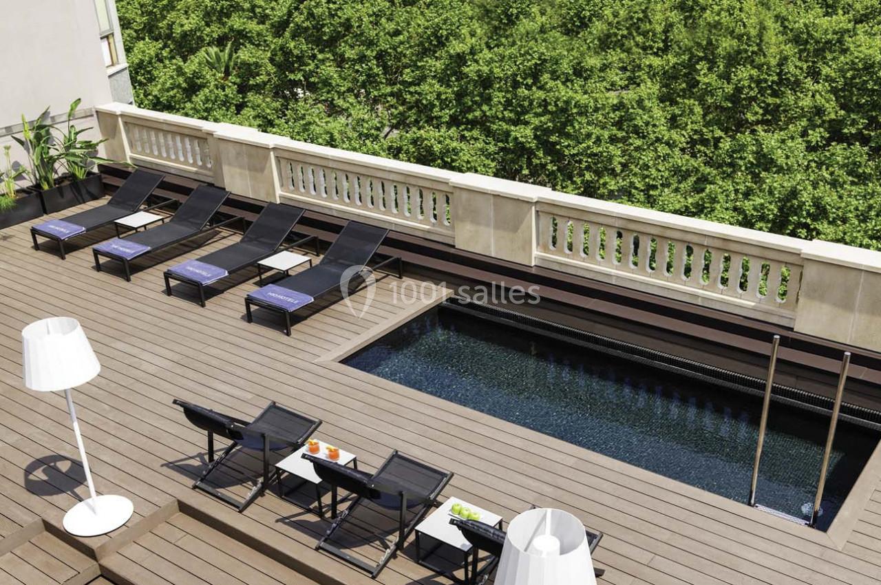 Terrasse en bois avec transats, petite piscine rectangulaire et vue sur des arbres verdoyants.