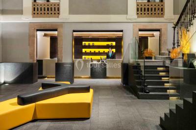 Salle de bain moderne avec douche vitrée, lavabo blanc, miroir rond, fleurs jaunes et mur bleu texturé.