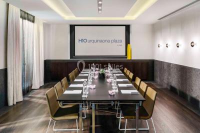 Salle de bain moderne avec douche vitrée, lavabo blanc, miroir rond, fleurs jaunes et mur bleu texturé.