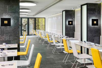 Salle de bain moderne avec douche vitrée, lavabo blanc, miroir rond, fleurs jaunes et mur bleu texturé.