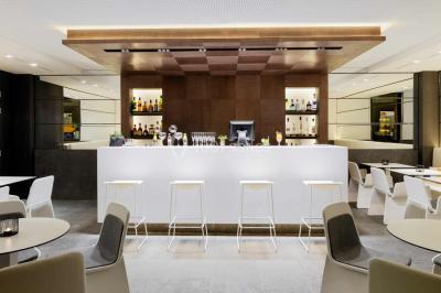 Salle de bain moderne avec douche vitrée, lavabo blanc, miroir rond, fleurs jaunes et mur bleu texturé.