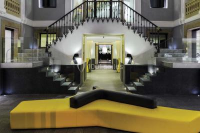 Salle de bain moderne avec douche vitrée, lavabo blanc, miroir rond, fleurs jaunes et mur bleu texturé.