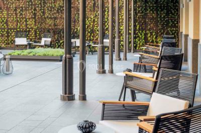 Salle de bain moderne avec douche vitrée, lavabo blanc, miroir rond, fleurs jaunes et mur bleu texturé.