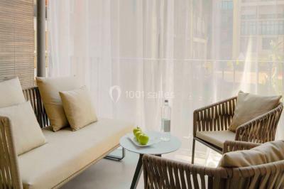 Salle de bain moderne avec douche vitrée, lavabo blanc, miroir rond, fleurs jaunes et mur bleu texturé.