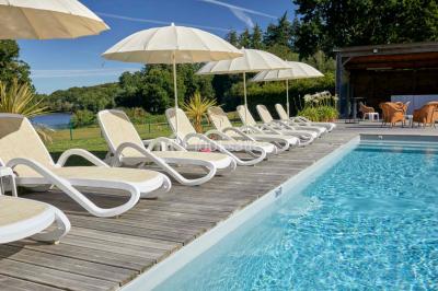Salle de réunion lumineuse avec poutres apparentes, tables en U dressées avec verres et chaises bleues.