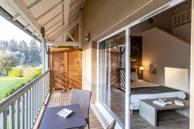 Salle de réunion lumineuse avec poutres apparentes, tables en U dressées avec verres et chaises bleues.