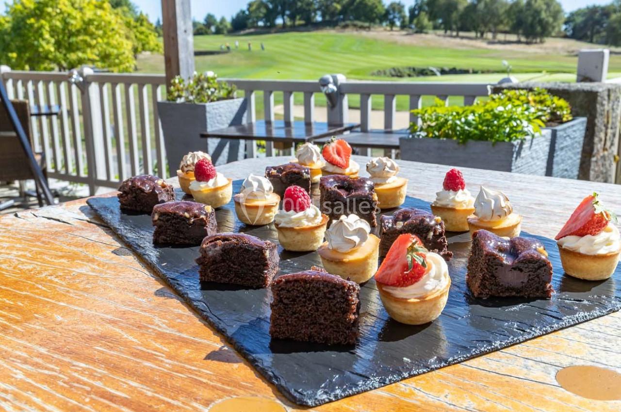 Assortiment de desserts miniatures, incluant gâteaux au chocolat et tartelettes aux fruits, présenté sur une ardoise.