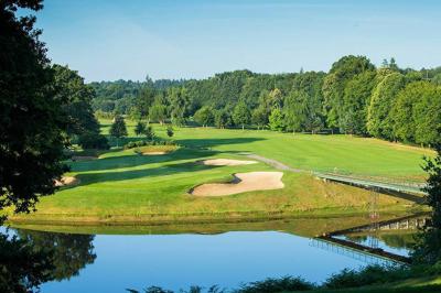Salle de réunion lumineuse avec poutres apparentes, tables en U dressées avec verres et chaises bleues.