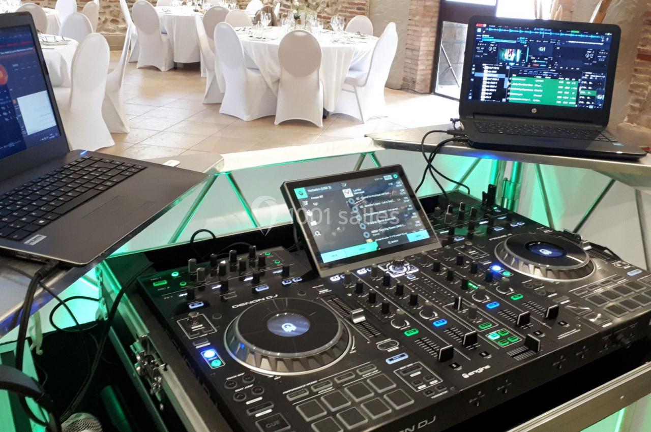 Équipement de DJ avec platines, table de mixage et ordinateurs portables dans une salle de réception.