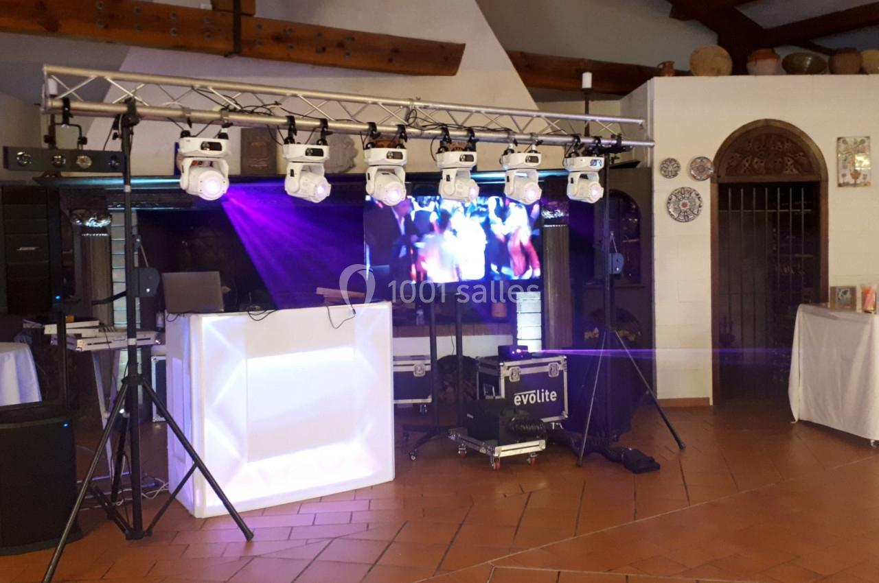 Installation de matériel de sonorisation et éclairage avec écran vidéo dans une salle au décor rustique.