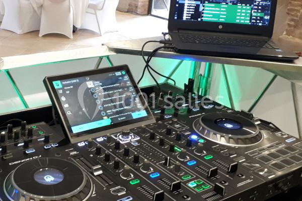 Poste de DJ avec une table de mixage, un ordinateur portable et une tablette affichant des playlists.