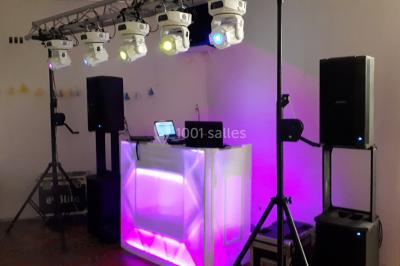 Salle de réception décorée avec des lumières colorées, des lanternes suspendues et un espace pour la musique et la danse.