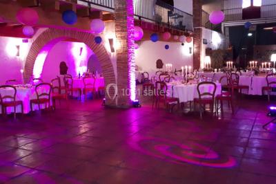 Salle de réception décorée avec des lumières colorées, des lanternes suspendues et un espace pour la musique et la danse.