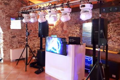 Salle de réception décorée avec des lumières colorées, des lanternes suspendues et un espace pour la musique et la danse.