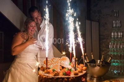 Gâteau de mariage décoré avec des choux, des fleurs en sucre et des cierges magiques allumés.