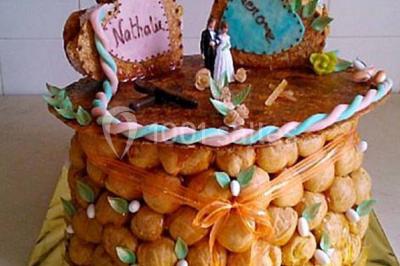Gâteau de mariage décoré avec des choux, des fleurs en sucre et des cierges magiques allumés.