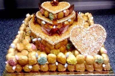 Gâteau de mariage décoré avec des choux, des fleurs en sucre et des cierges magiques allumés.