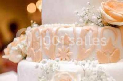 Gâteau de mariage décoré avec des choux, des fleurs en sucre et des cierges magiques allumés.