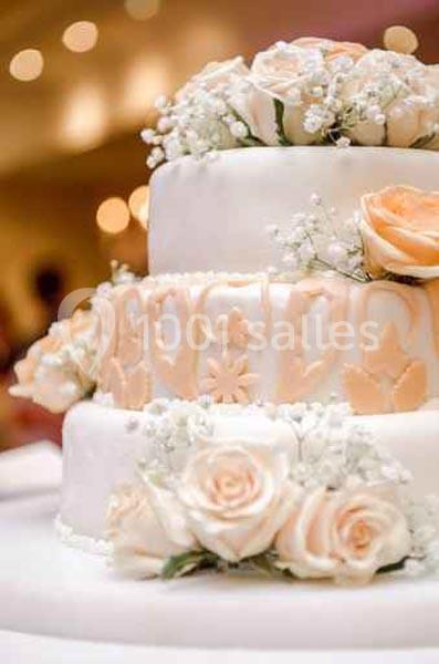 Gâteau de mariage à trois étages décoré de roses blanches et pêche ainsi que de gypsophiles.