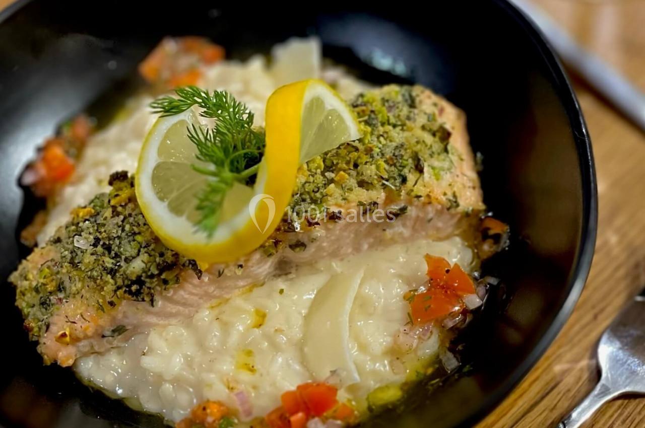 Filet de saumon en croûte d'herbes servi sur un risotto crémeux, garni de citron et d'aneth.