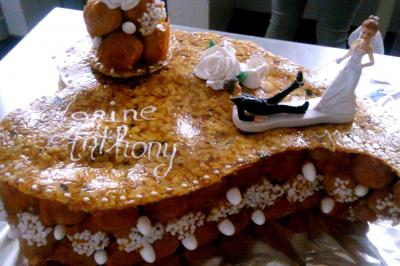 Gâteau de mariage décoré avec des choux, des fleurs en sucre et des cierges magiques allumés.