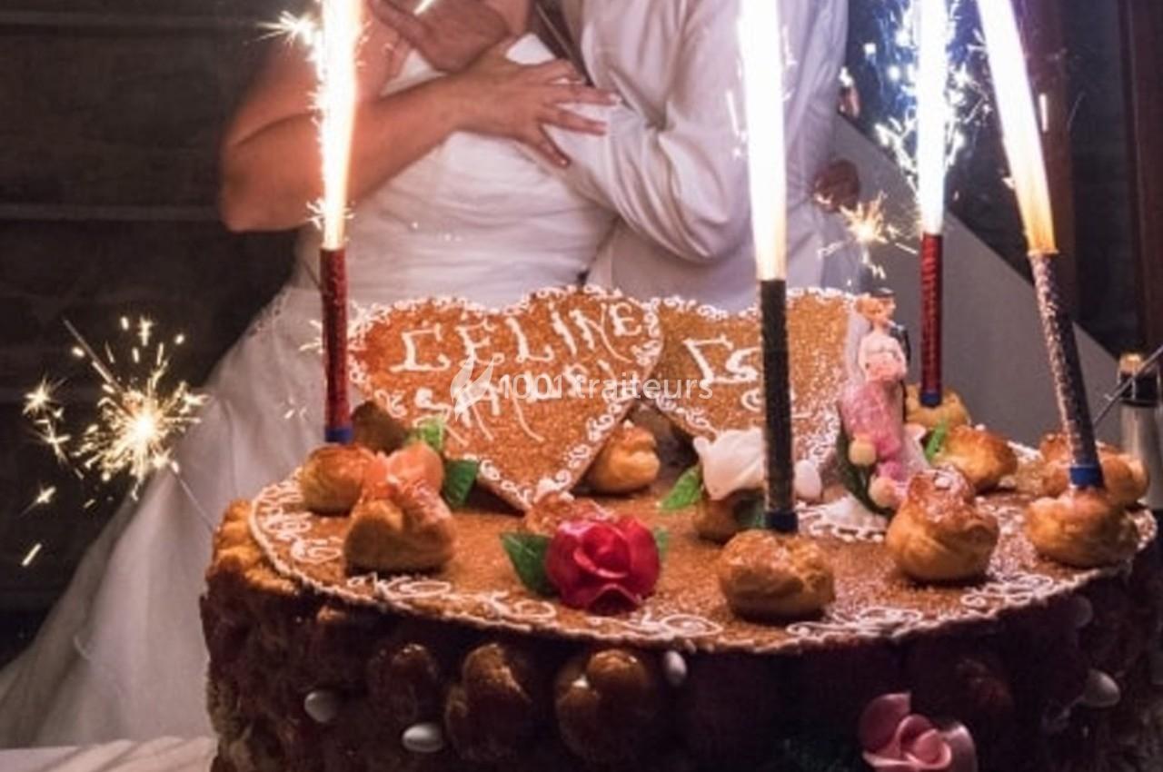 Gâteau de mariage décoré avec des choux, des fleurs en sucre et des cierges magiques allumés.