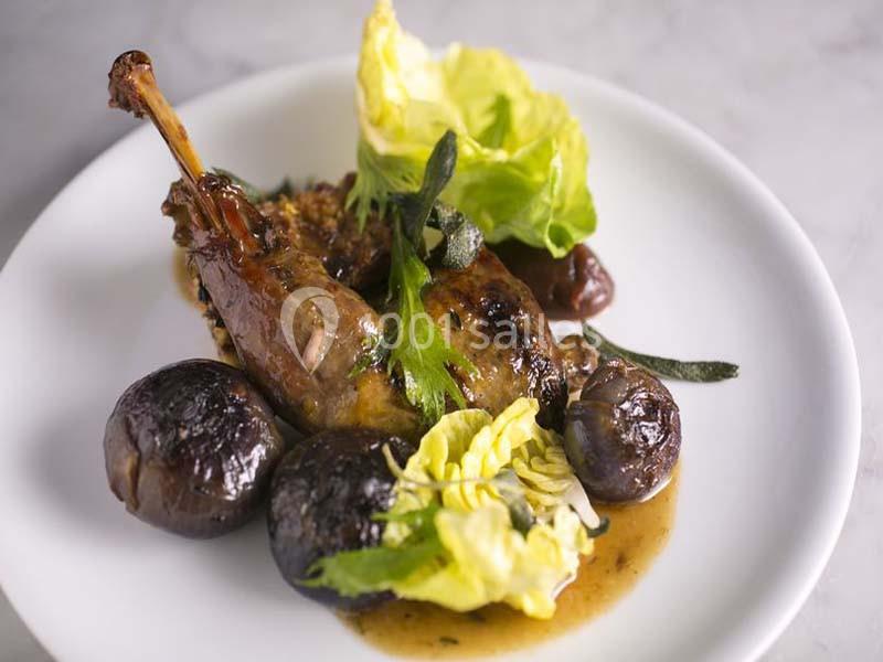 Assiette de cuisse de volaille confite avec champignons rôtis, salade verte et sauce, servie sur une table en marbre.