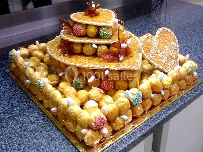 Pièce montée en choux caramélisés décorée de dragées et de nougatine, posée sur un plan de travail.