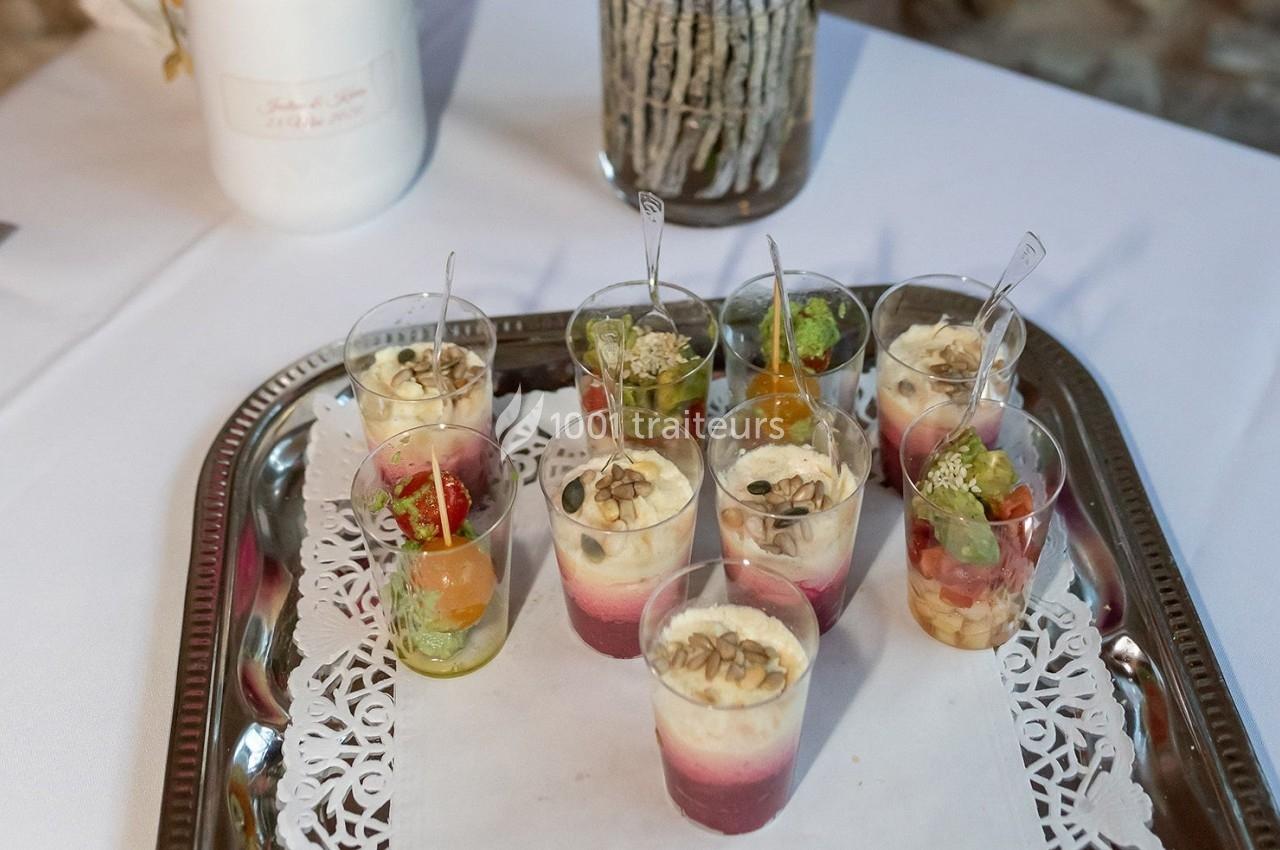 Plateau de verrines variées avec des ingrédients colorés et des décorations, présenté sur une nappe blanche.