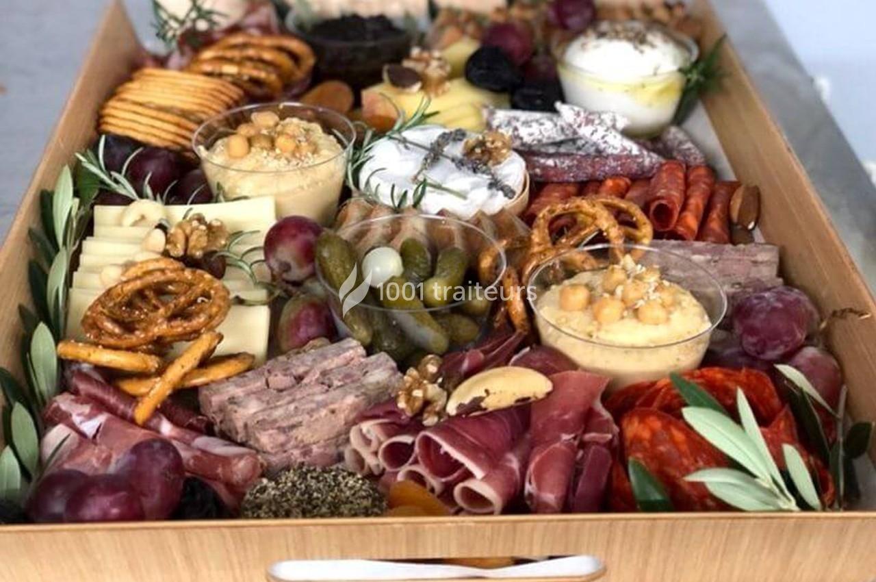 Plateau en bois garni de charcuteries, fromages, fruits, légumes marinés, crackers et dips variés.