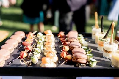 Assortiment de bouchées gastronomiques sur une planche en bois, incluant tartes aux légumes et poissons garnis.