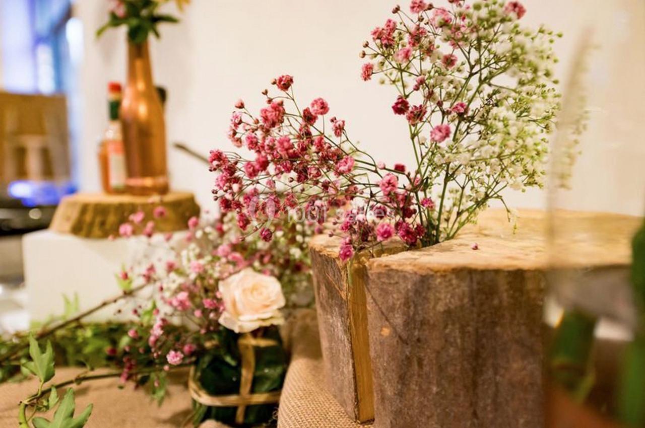 Fleurs roses et blanches disposées dans un décor rustique avec des éléments en bois et des touches végétales.