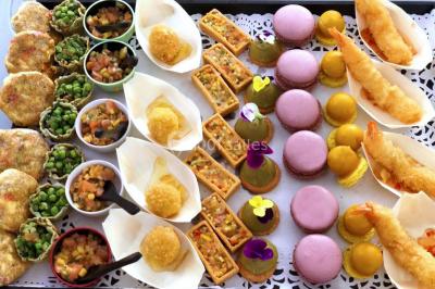 Assortiment de bouchées gastronomiques sur une planche en bois, incluant tartes aux légumes et poissons garnis.