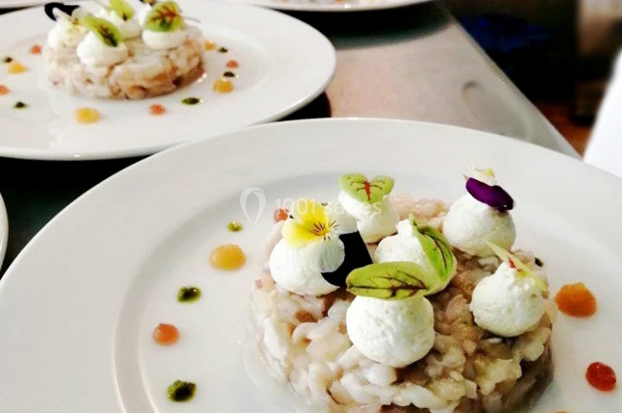 Assiette de risotto dressée avec des quenelles de fromage, herbes fraîches et fleurs comestibles.