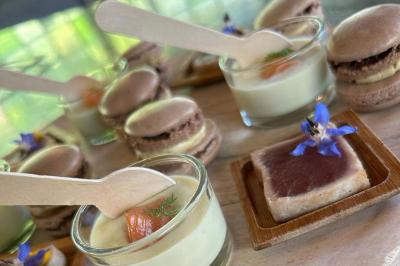 Assortiment de bouchées gastronomiques sur une planche en bois, incluant tartes aux légumes et poissons garnis.