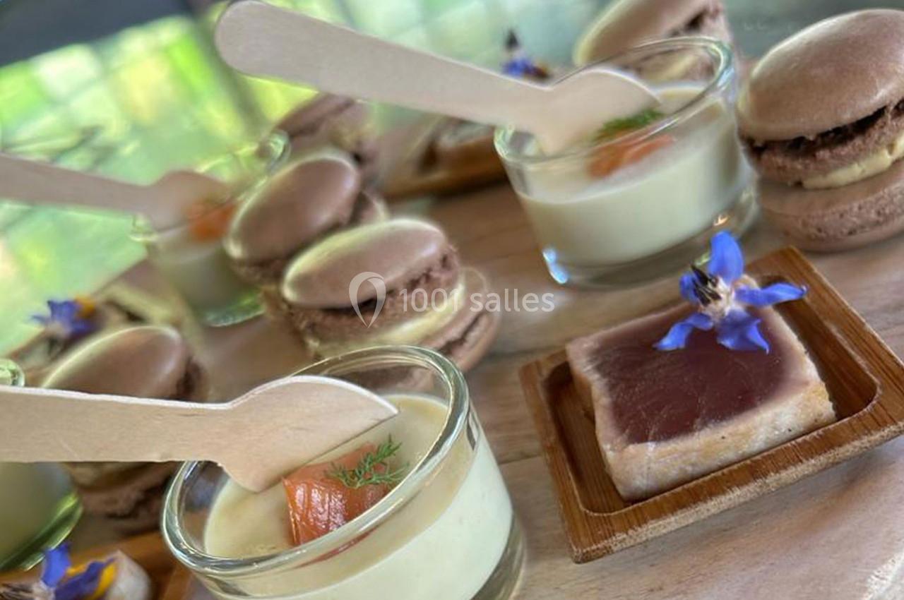 Assortiment de verrines, macarons et bouchées sucrées-salées présentés sur un plateau en bois.